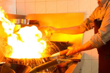 Asian restaurant chef cooking food in a wok